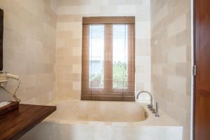 a large tub in a bathroom with a window at Villa Annecy in Seminyak +86 photos