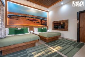 two beds in a room with a painting on the wall at StayVista at Aura Farmstay with Pool & Lawn in Badlapur +21 photos
