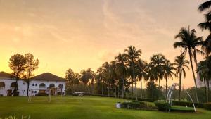 ein Haus mit Palmen vor einem Feld in der Unterkunft Ponderosa Golf & Country Resort in Johor Bahru
