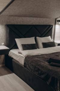 Un dormitorio con una cama grande con cabecero negro. en Forest Cliff Славське, en Slavske