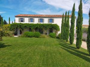a house with trees in front of a yard at Mas de charme au pied des Alpilles in Maussane-les-Alpilles