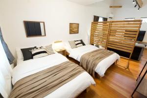 two beds in a room with white walls and wood floors at アーモンド石垣 in Tunugusuku