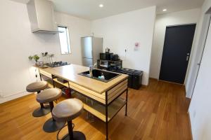 a kitchen with a sink and a counter with stools at アーモンド石垣 in Tunugusuku