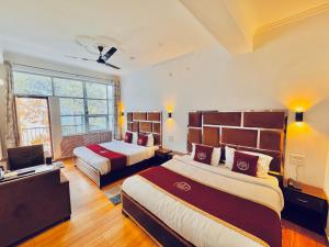una camera d'albergo con due letti e una televisione di The Ambience Resort, Nainital - A Hidden Gem Away From City Hustle a Nainital