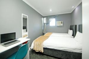 una camera da letto con un letto e una scrivania con un computer di City view lodge a Città del Capo