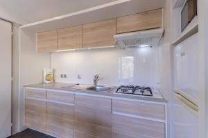 a white kitchen with a sink and a stove at Mobilhome O’Hara 884 in Bouzic