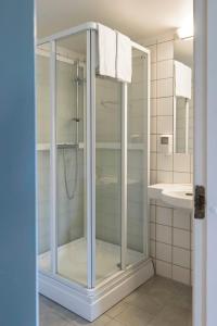 a glass shower in a bathroom with a sink at Victoria hotell & apartments Fredrikstad in Fredrikstad