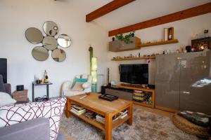 a living room with a couch and a table and a tv at La Villa du bonheur in Puy-Saint-Martin