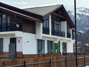 a house with a wooden fence in front of it at Eco Cottage BaBi in Bakuriani