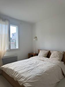 Una cama blanca en un dormitorio con ventana. en Charmante villa à istres, en Istres