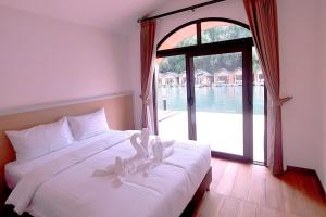 Un dormitorio con una cama blanca con una ventana grande. en Daoneua Riverside Resort, en Muang Fuang