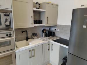 a kitchen with white cabinets and a stainless steel refrigerator at Hampden Glasgow Tenement Flat in Glasgow