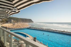 a swimming pool next to a beach and the ocean at Arribas Sintra Hotel in Sintra