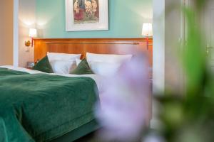 a bedroom with a bed with green sheets and pillows at Romantik Hotel Kleber Post in Bad Saulgau