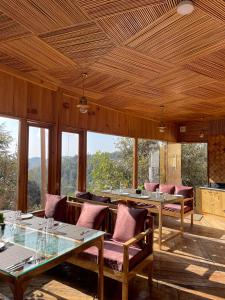 a dining room with tables and chairs and windows at The Golden Castle Hotels in Mukteswar