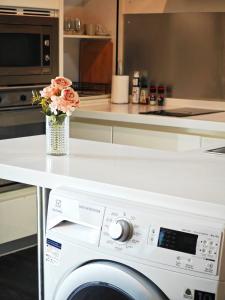 a kitchen with a washing machine with a vase of flowers at City comfort appartment, Skytain Step 600 m, Erawan shrine in Bang Kapi