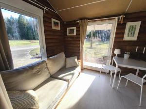 a living room with a couch and a table and a window at Rozes Oga, Tūrisma mītnes namiņš in Ieriķi