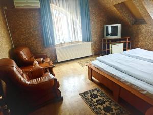 a bedroom with a bed and two chairs and a tv at Hotel Christine in Târgu Secuiesc