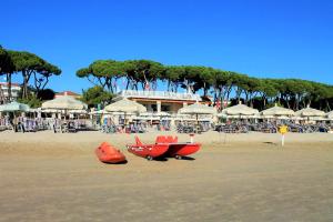 una spiaggia con barca rossa, sedie e ombrelloni di Leopardi Pineto Vacanza a Pineto