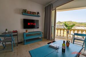 a living room with a tv and a view of a balcony at A holiday Home in Gozo Right by the Sea in Marsalforn