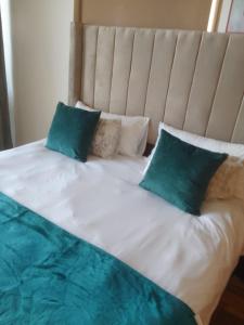 Una cama blanca con dos almohadas verdes encima. en Lighthouse Apts Balcony apartment, en Durban