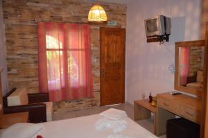a bedroom with a bed and a tv and a window at Penzion Blo in Panormos Skopelos
