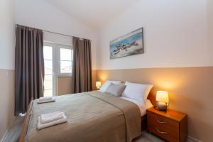 a bedroom with a bed with two lamps and a window at Villa K&F Borik in Zadar