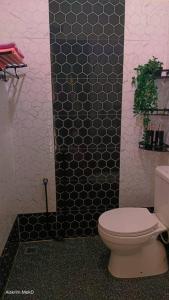 a bathroom with a toilet and a black tiled wall at Dee Riverside Homestay airport kota Bharu in Kota Bharu