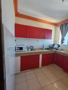 a small kitchen with red cabinets and a microwave at Luxury holiday apartments in Mombasa