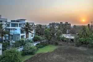 vista para uma cidade ao pôr-do-sol com palmeiras em SaffronStays Skylight em Alibag