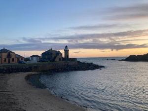 a lighthouse on the shore of a body of water at Cosy Holiday Home Portpatrick in Portpatrick