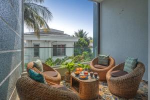 uma varanda com cadeiras de vime e uma mesa com velas em SaffronStays Skylight em Alibag