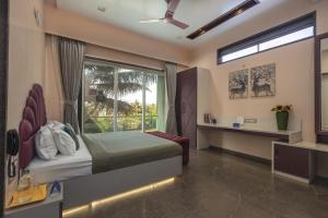 a bedroom with a bed and a large window at SaffronStays Skylight in Alibaug