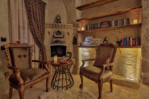 a living room with two chairs and a table and a fireplace at Asuwari Suites Cappadocia in Ürgüp