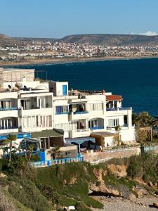 a large white building on a hill next to the water at dar al bahar Taghazout -beachfront Apartment in Taghazout