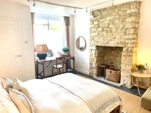 a bedroom with a stone fireplace and a bed at New The Barley Rustic luxury in Cirencester