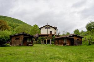 a house and two huts in a field at Hotel Rural Picos de Europa in Posada de Valdeón