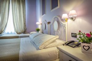 Hotel Ferrucci في فلورنسا: غرفة نوم بسرير ابيض وطاولة مع هاتف