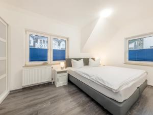 biała sypialnia z łóżkiem i dwoma oknami w obiekcie Ferienwohnung Meeresbrise in der Residenz Clara Sophia w mieście Binz