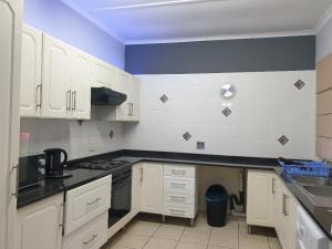 een keuken met witte kasten en een blauwe muur bij Meerensee Cottage in Richards Bay