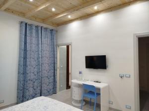 a bedroom with a desk and a tv on a wall at Il Cortile Fiorito in Trapani