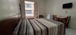 a bedroom with a bed with a striped blanket at Hotel Plaza Olido in Sao Paulo