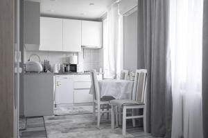a kitchen with white cabinets and a table and chairs at Stylish Cozy Apartment, Near Chisinau Center in Chişinău