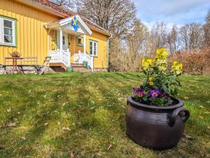 a yellow house with a pot of flowers in the yard at Sotanäs Huldas in Fegen