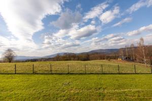 a field of green grass with a fence at Henry Domki - prywatna sauna i jacuzzi in Żywiec