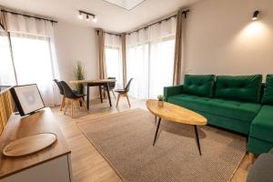 a living room with a green couch and a table at Henry Domki - prywatna sauna i jacuzzi in Żywiec