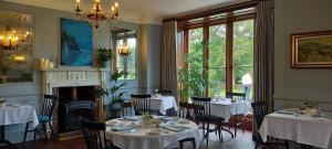 a dining room with tables and chairs and a fireplace at Parc-Le-Breos House in Penclawdd