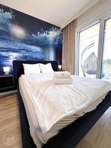 a bedroom with a large bed with a painting on the wall at Apartament na wydmie - Perłowa Przystań in Sianozety