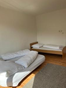 a room with three beds with white sheets and a rug at Bergblick Balkon Bruck an der Mur in Bruck an der Mur