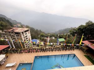 a building with a swimming pool and mountains in the background at Hotel Tempo Heritage Resort In Gangtok in Gangtok